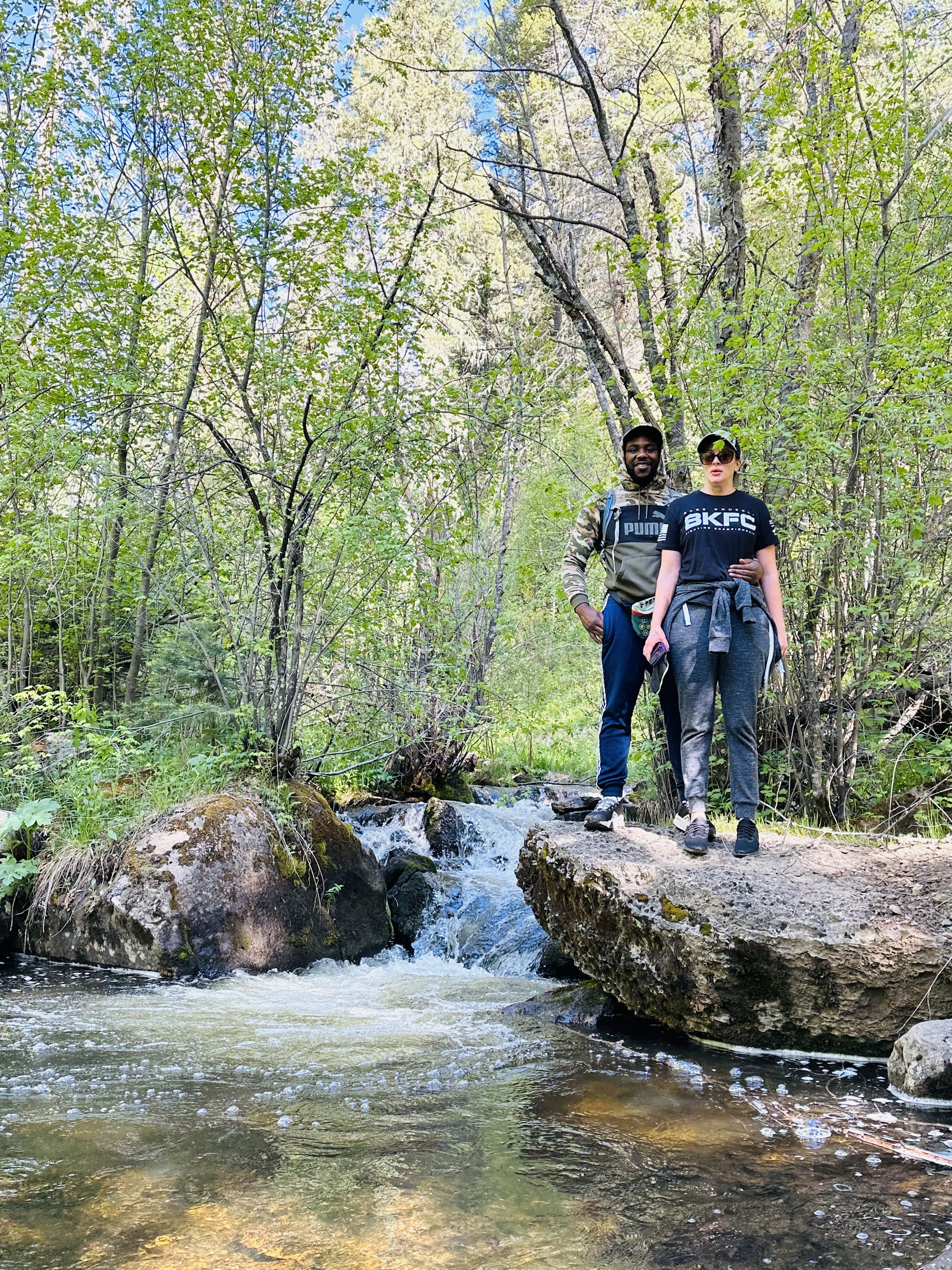 Guests standing on rocks by a waterfall on the Pecos Wilderness trail