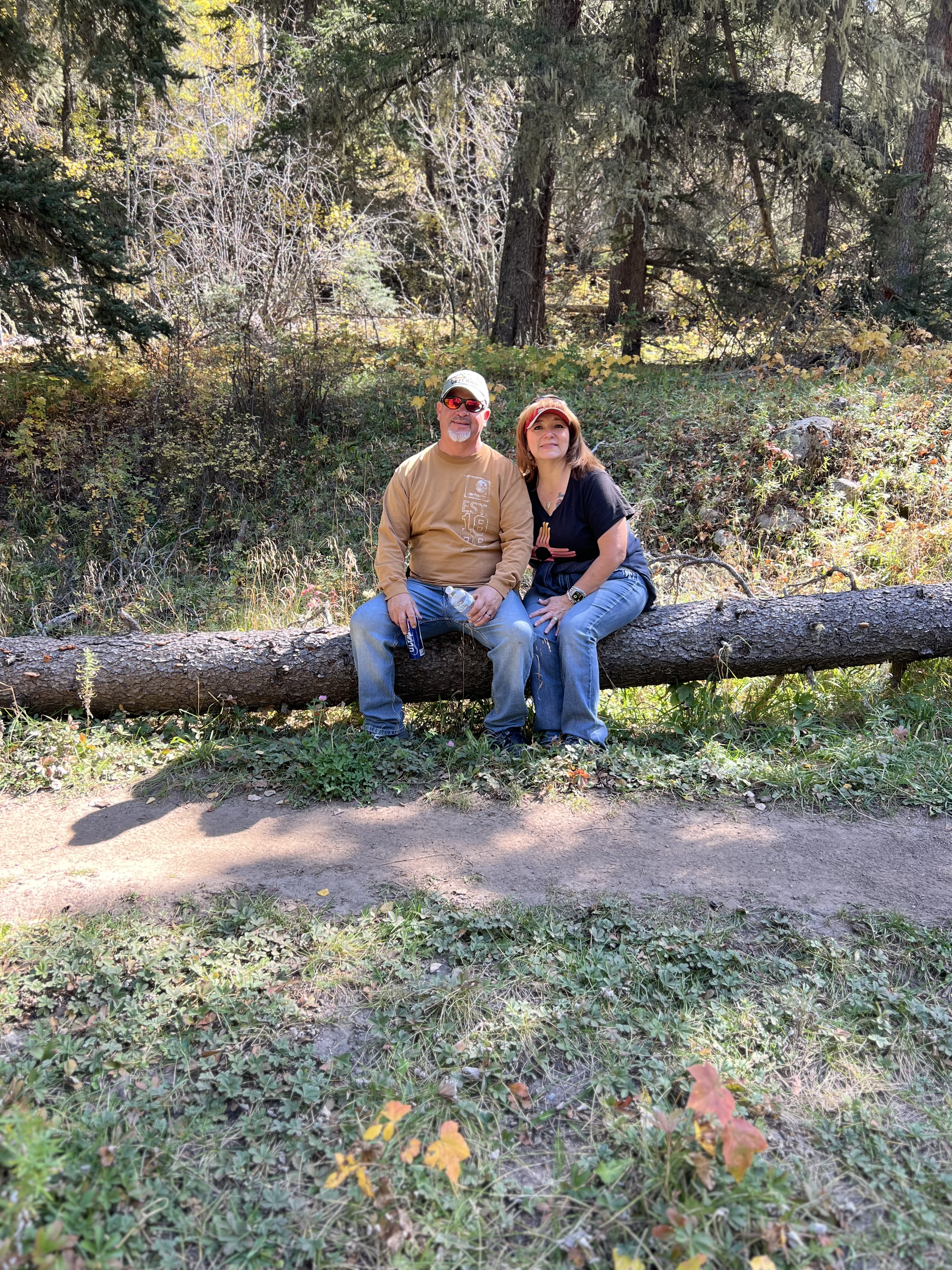 Guests resting on fallen log on hiking trail Pecos Canyon